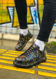 Colorful sneakers with black soles worn on a yellow tactile paving surface.