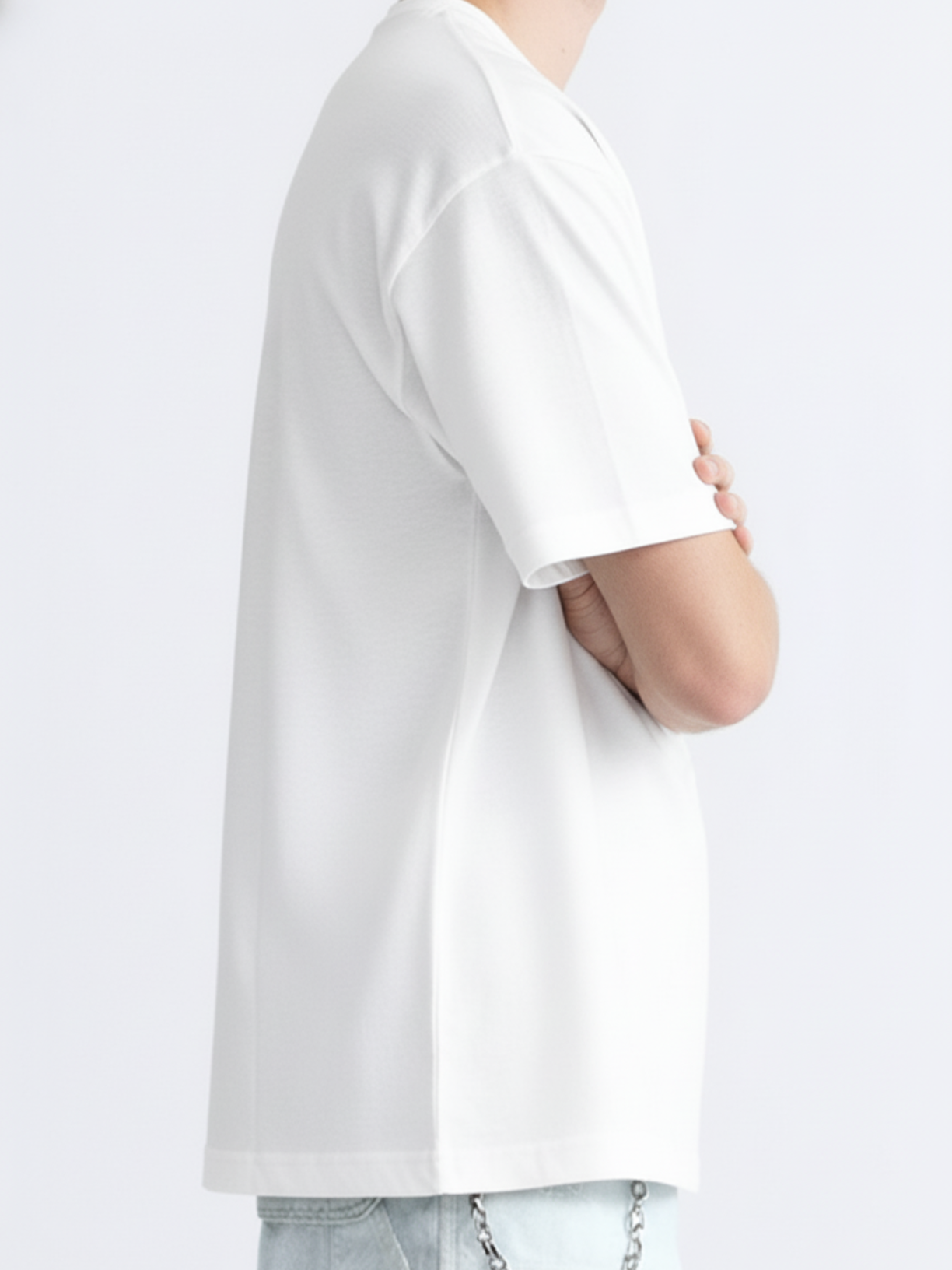 Person wearing a plain white t-shirt on a light gray background