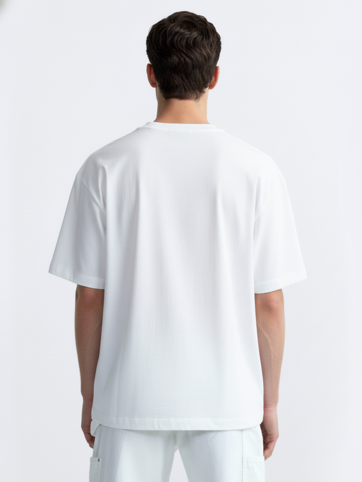 Person wearing a plain white t-shirt and pants on a light gray background