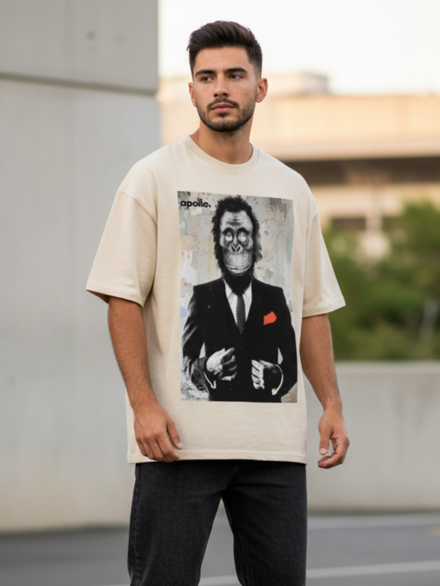 Man wearing a beige t-shirt with a graphic design, standing on a street.