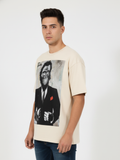 Man wearing a cream t-shirt with a graphic of a monkey in a suit on a white background