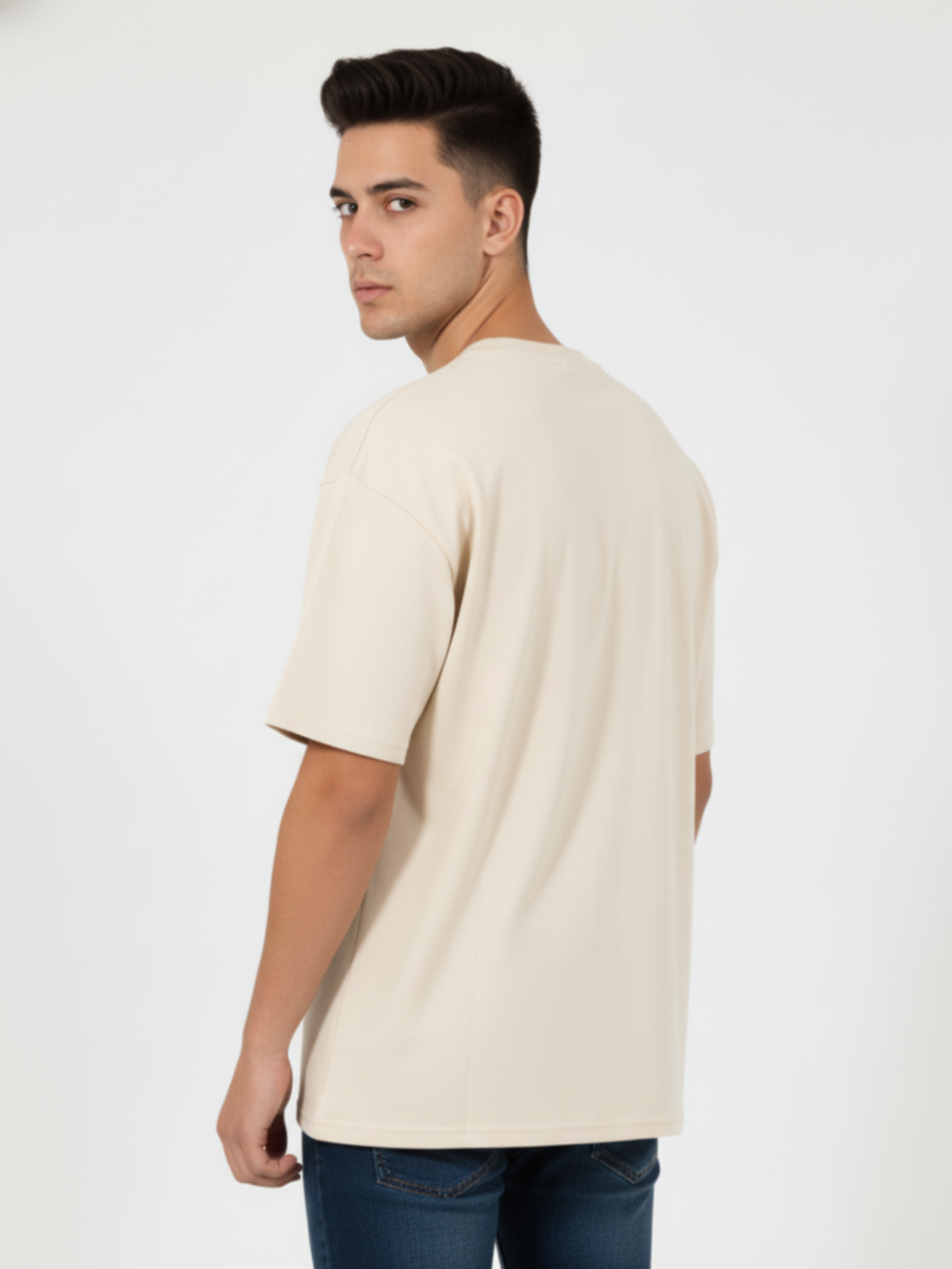 Man wearing a beige t-shirt and blue jeans on a white background