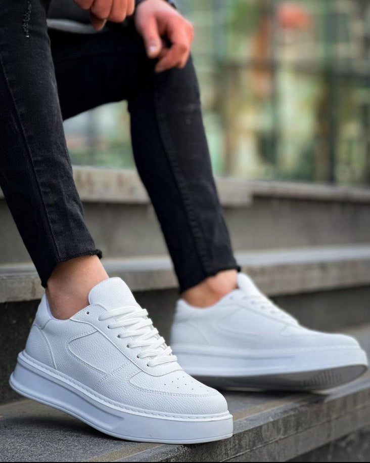 White sneakers worn with black pants on a blurred outdoor background