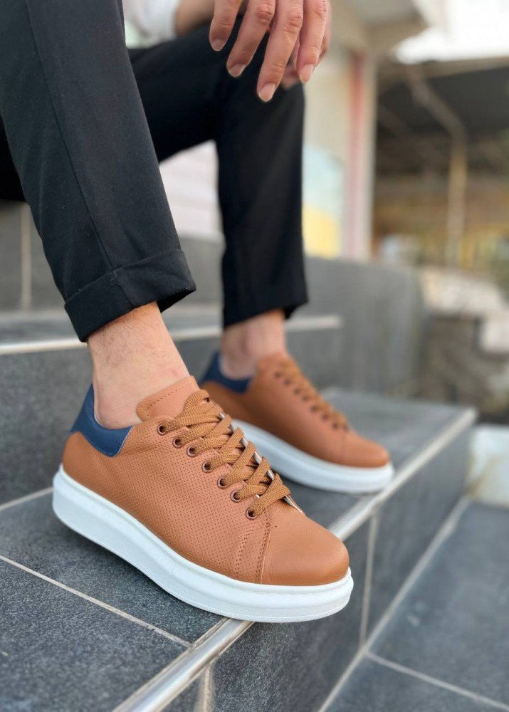 Brown sneakers with white soles worn by a person on stone steps.