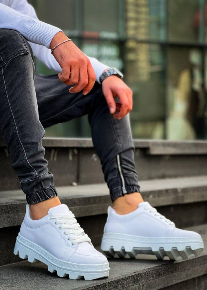 White sneakers with thick soles worn by a person on steps.