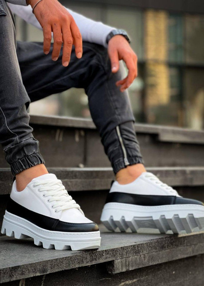 White sneakers with black accents on a person sitting on steps.
