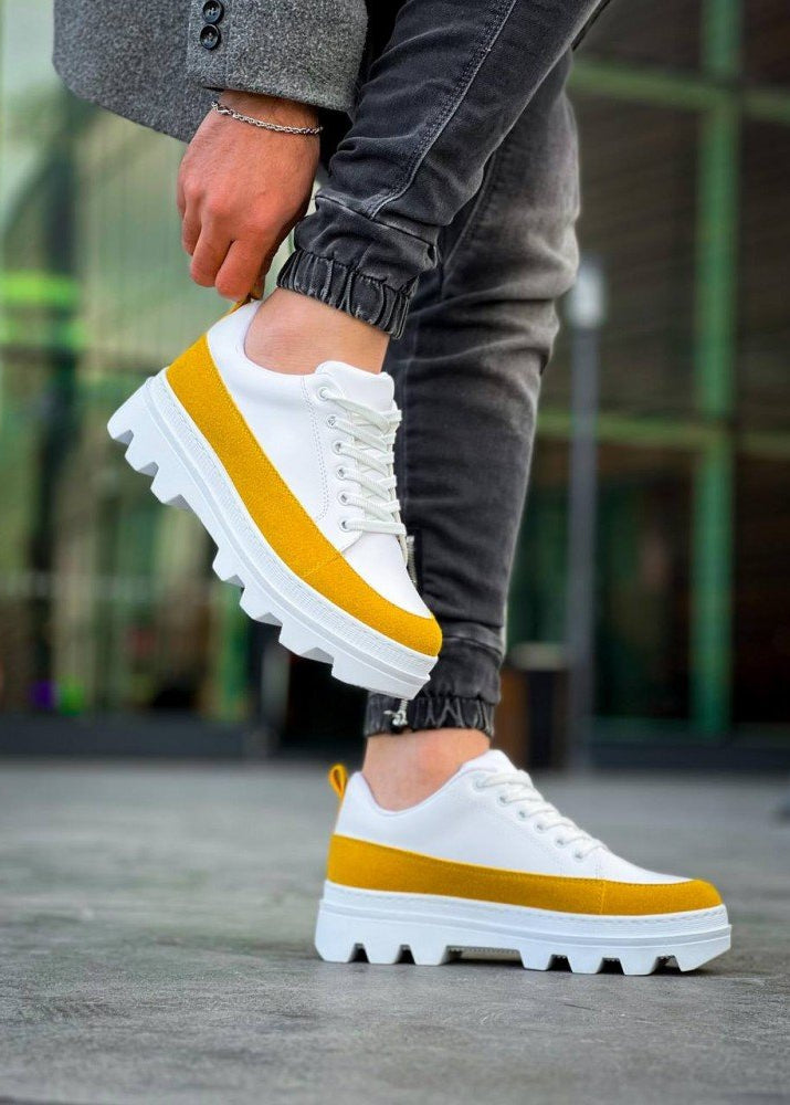 White sneakers with yellow stripes worn by a person on a blurred background