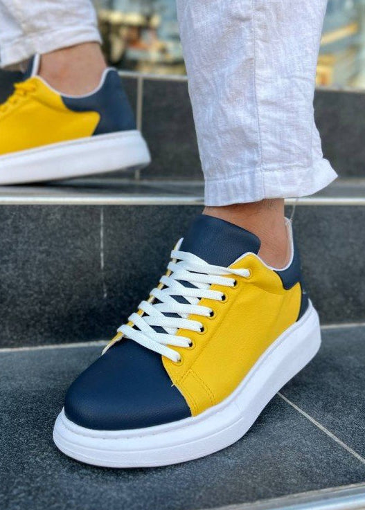 Yellow and navy sneakers with white soles worn on a step.