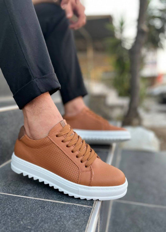 Brown sneaker with white sole worn outdoors on a stone surface