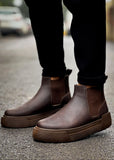 Close-up of Avalon Coffee Brown Chelsea boots worn outdoors on wet pavement.
