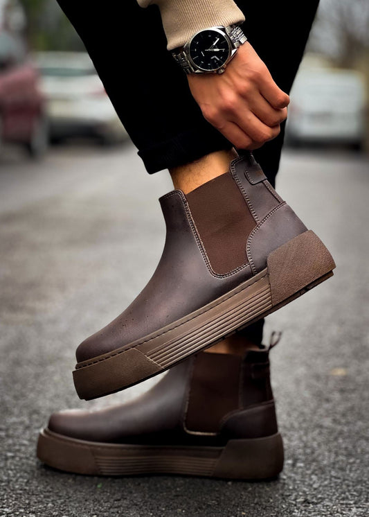 Close-up of Avalon Coffee Brown Chelsea boots worn outdoors on wet pavement.