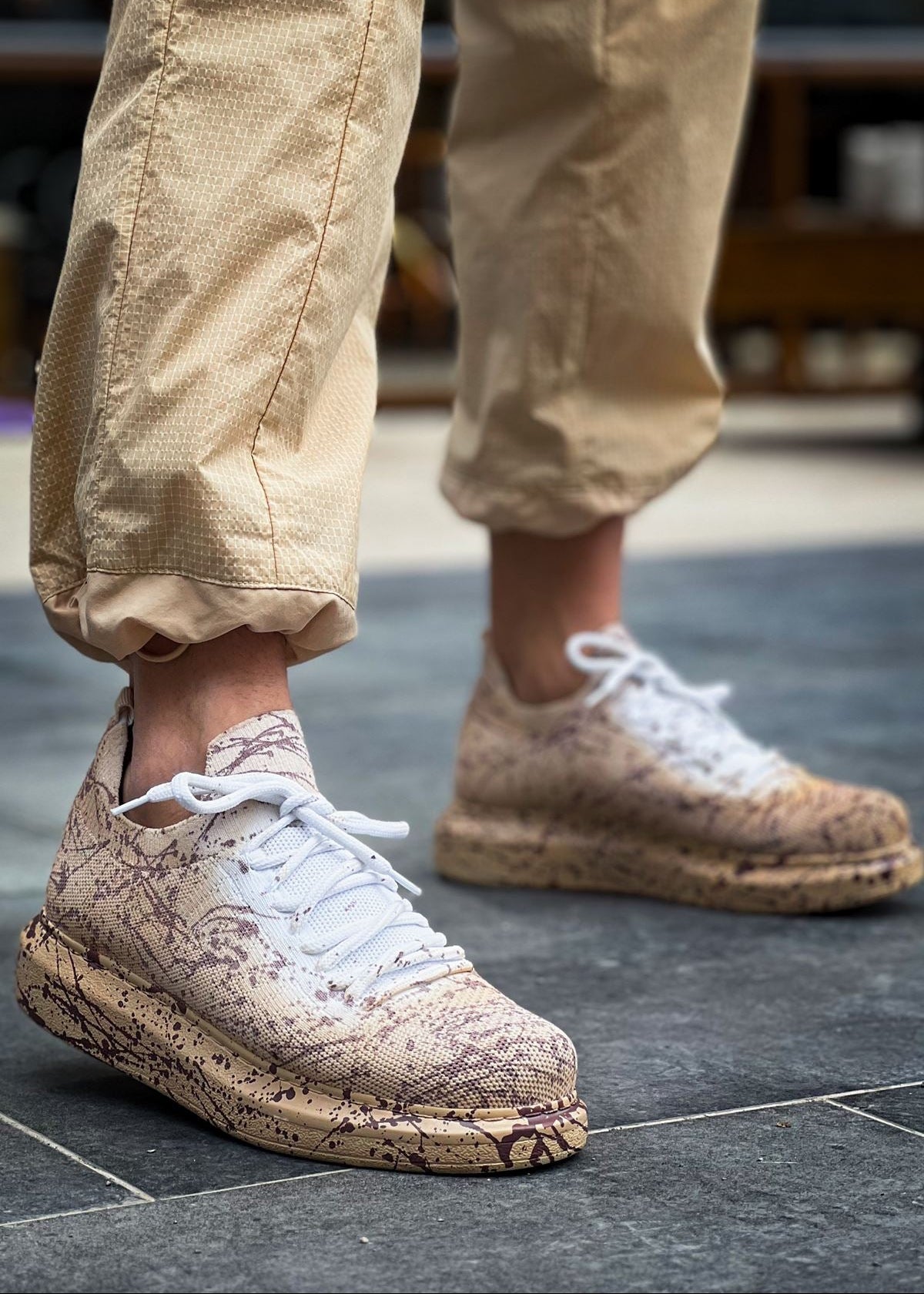 Man wearing Torino Light Brown Peak sneakers with hand-painted splatter design and white laces.