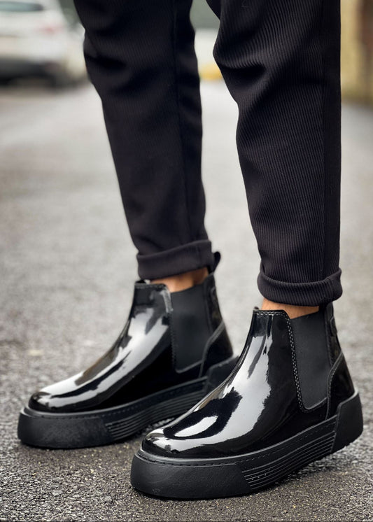 Close-up of black patent Avalon Chelsea Apollo boots worn outdoors with black pants.