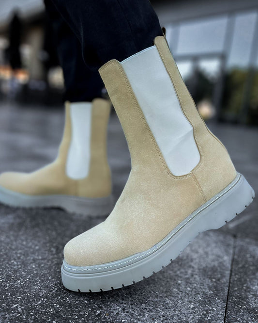 Lifestyle shot of Zenith Sand Chelsea Boots by Apollo Moda in beige suede with white elastic panels and gray soles worn outdoors.