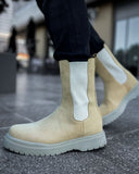 Lifestyle shot of Zenith Sand Chelsea Boots by Apollo Moda in beige suede with white elastic panels and gray soles worn outdoors.